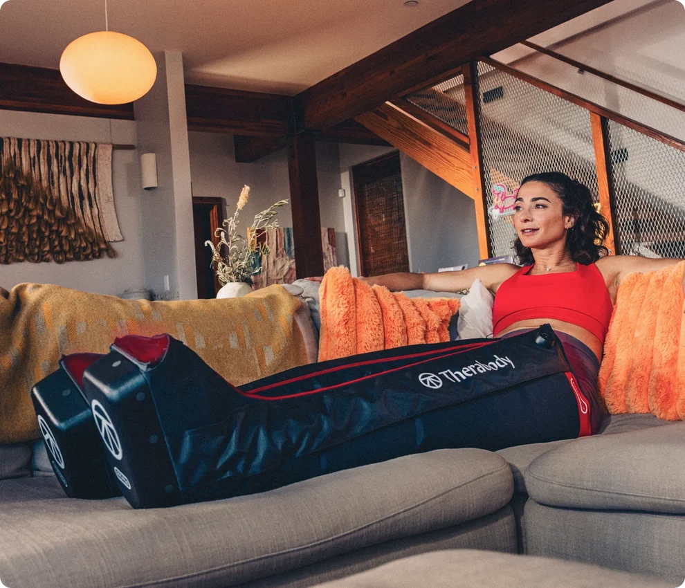 Person relaxing on a sofa using compression recovery boots